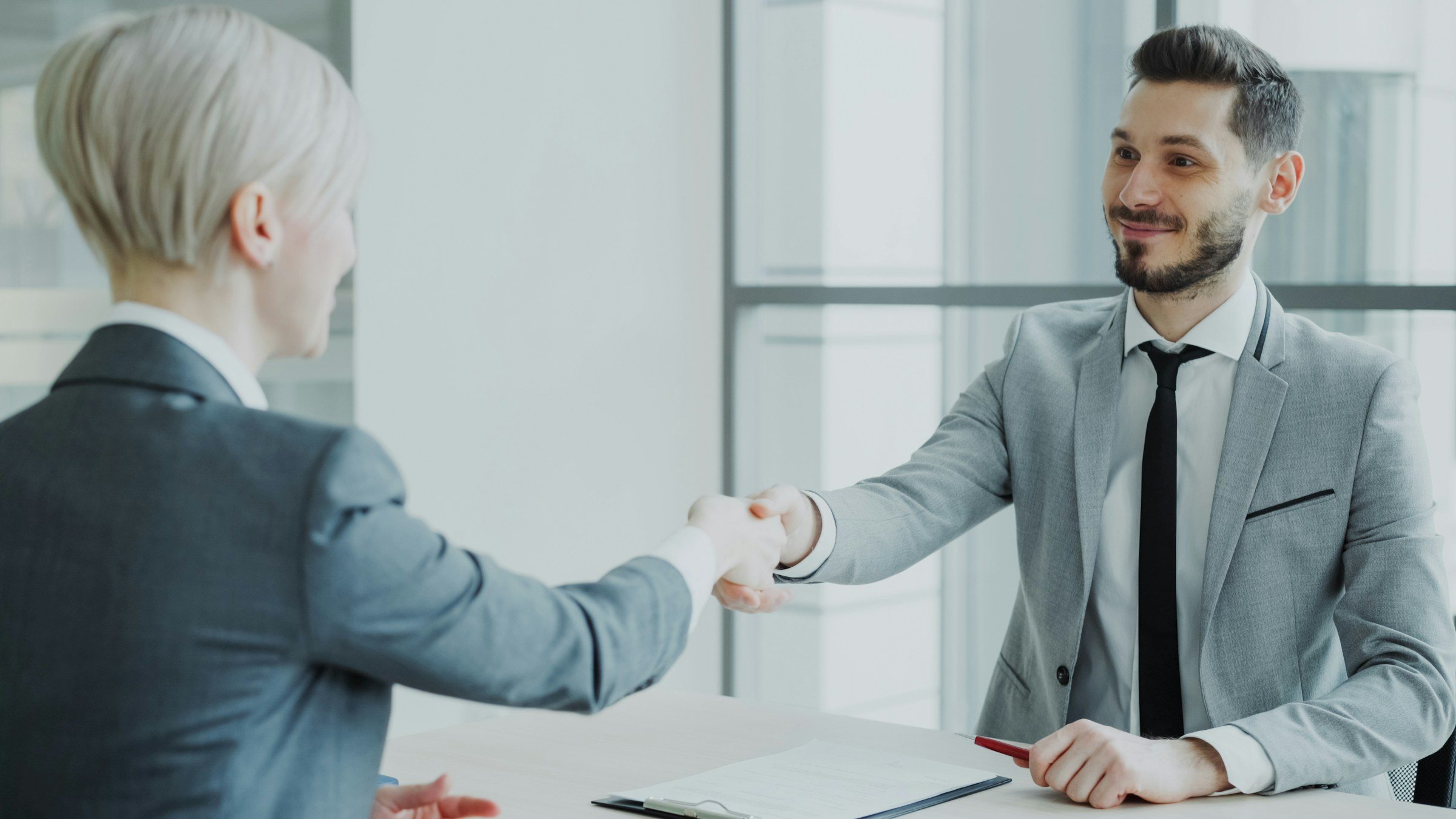 Two people shaking hands across a meeting table